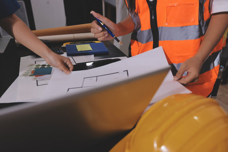 Closeup of team of industrial engineers meeting analyze machinery blueprints consult project on table in manufacturing factory. Working in manufacturing plant or production plant.の写真素材
