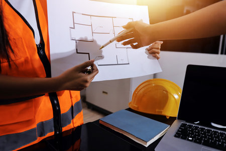 Closeup of team of industrial engineers meeting analyze machinery blueprints consult project on...
