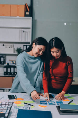 UX UI designer testing prototype on a phone, discussing and brainstorming on wireframes for a website and mobile app prototype, in the concept of website and mobile application design concept.の写真素材