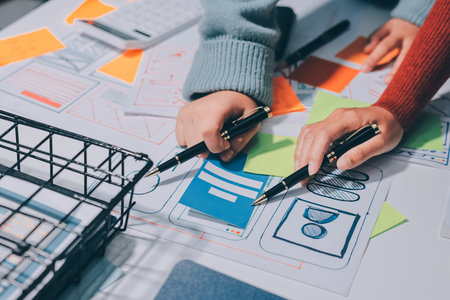 UX UI designer testing prototype on a phone, discussing and brainstorming on wireframes for a...