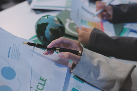 Asian woman lead young group of multiethnic businesspeople in team meeting, using laptop computer for ESG topic presentation on monitor. Sustainable business practice, people work at home conceptの写真素材