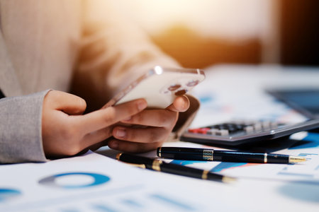 Business woman using calculator and writing make note with calculate. Woman working at office with laptop and documents on his deskの写真素材