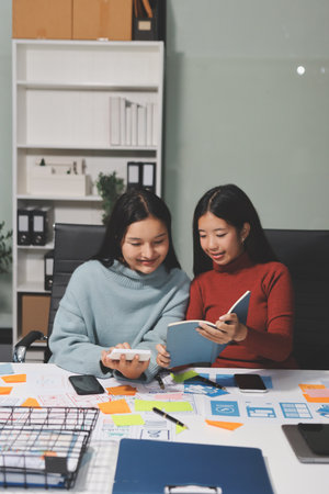 UX UI designer testing prototype on a phone, discussing and brainstorming on wireframes for a website and mobile app prototype, in the concept of website and mobile application design concept.の写真素材