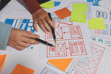 UX UI designer testing prototype on a phone, discussing and brainstorming on wireframes for a website and mobile app prototype, in the concept of website and mobile application design concept.の写真素材