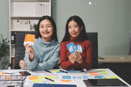 UX UI designer testing prototype on a phone, discussing and brainstorming on wireframes for a website and mobile app prototype, in the concept of website and mobile application design concept.の写真素材