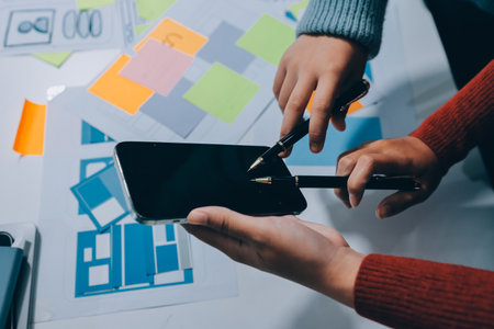 UX UI designer testing prototype on a phone, discussing and brainstorming on wireframes for a website and mobile app prototype, in the concept of website and mobile application design concept.の写真素材
