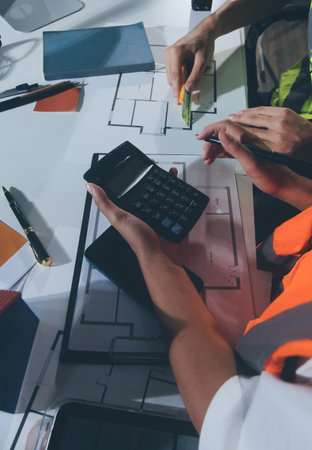 Closeup of team of industrial engineers meeting analyze machinery blueprints consult project on...