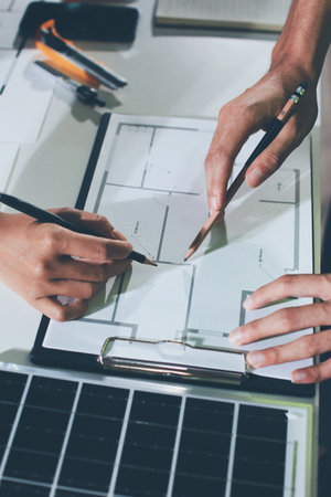 Closeup of team of industrial engineers meeting analyze machinery blueprints consult project on...