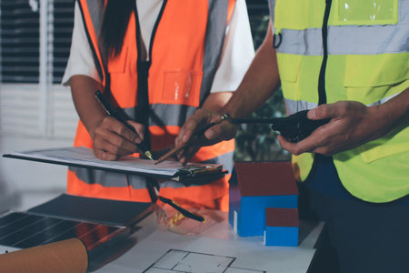 Closeup of team of industrial engineers meeting analyze machinery blueprints consult project on...