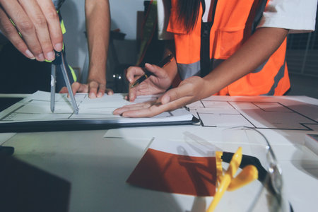 Closeup of team of industrial engineers meeting analyze machinery blueprints consult project on...