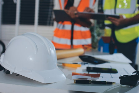 Closeup of team of industrial engineers meeting analyze machinery blueprints consult project on...