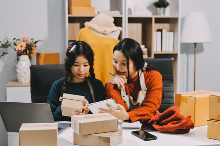 Portrait of Starting small businesses SME owners, two Asian woman check online orders Selling products working with boxs freelance work at home office, sme business online small medium enterpriseの写真素材