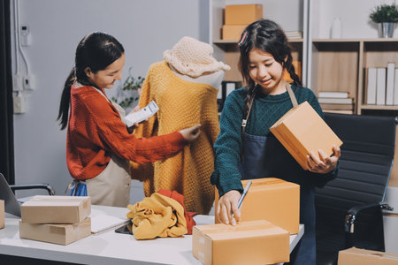 Portrait of Starting small businesses SME owners, two Asian woman check online orders Selling products working with boxs freelance work at home office, sme business online small medium enterpriseの写真素材
