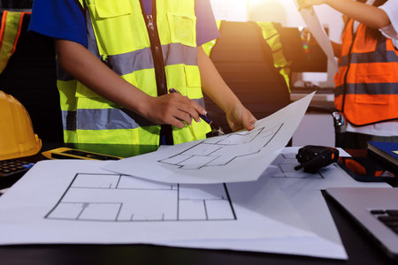 Closeup of team of industrial engineers meeting analyze machinery blueprints consult project on...