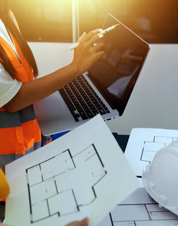 Closeup of team of industrial engineers meeting analyze machinery blueprints consult project on...