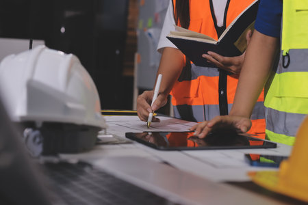 Closeup of team of industrial engineers meeting analyze machinery blueprints consult project on...