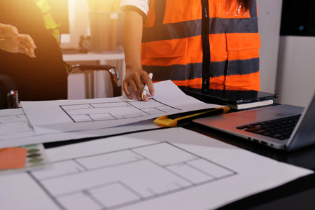 Closeup of team of industrial engineers meeting analyze machinery blueprints consult project on...