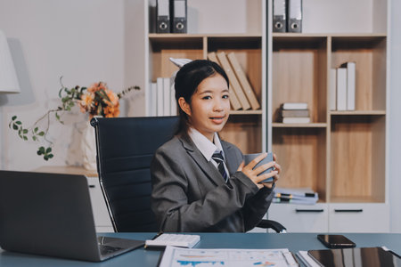 Asian Businesswoman Using laptop computer and working at office with calculator document on desk,...