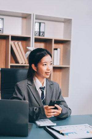 Portrait of a happy Asian businesswoman using mobile phone indoor, Asian businesswoman working in modern office.の写真素材