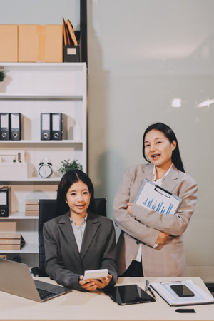 Entrepreneur Asian businessman and businesswoman discussing new business project in tablet in modern Meeting In Modern Office, Asian business casual concept.の写真素材