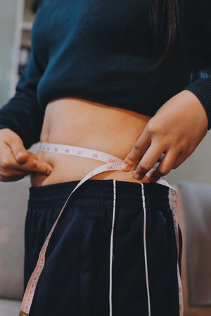 woman's hand holding excessive belly fat, overweight concept