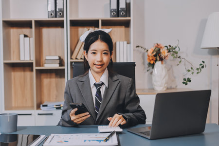 Portrait of a happy Asian businesswoman using mobile phone indoor, Asian businesswoman working in...