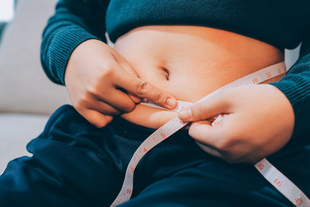 woman's hand holding excessive belly fat, overweight concept