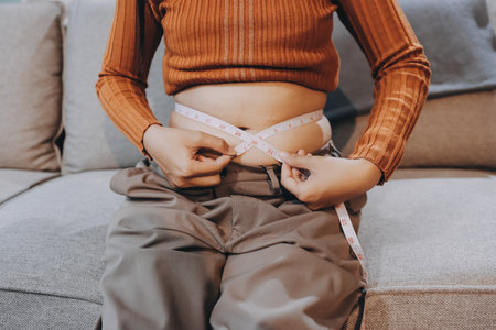 woman's hand holding excessive belly fat, overweight concept