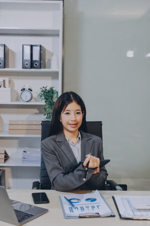 Portrait of Young Asian woman hand freelancer is working her job on computer tablet in modern office. Doing accounting analysis report real estate investment data, Financial and tax systems concept.の写真素材