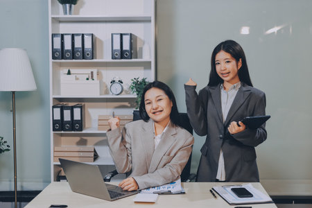 Entrepreneur Asian businessman and businesswoman discussing new business project in tablet in modern Meeting In Modern Office, Asian business casual concept.の写真素材