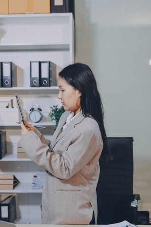 Entrepreneur Asian businessman and businesswoman discussing new business project in tablet in modern Meeting In Modern Office, Asian business casual concept.の写真素材
