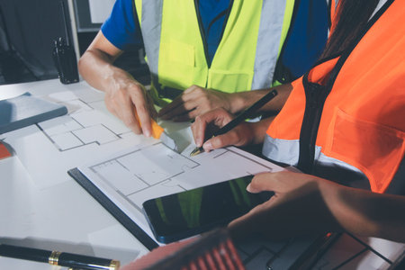 Closeup of team of industrial engineers meeting analyze machinery blueprints consult project on...
