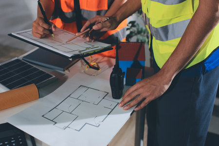 Closeup of team of industrial engineers meeting analyze machinery blueprints consult project on...