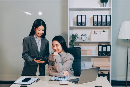 Entrepreneur Asian businessman and businesswoman discussing new business project in tablet in modern Meeting In Modern Office, Asian business casual concept.の写真素材