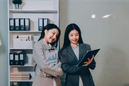 Entrepreneur Asian businessman and businesswoman discussing new business project in tablet in modern Meeting In Modern Office, Asian business casual concept.の写真素材