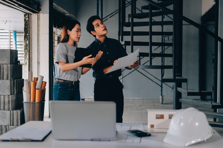 Construction manager and engineer explore construction documentation on the building site near the steel framesの写真素材