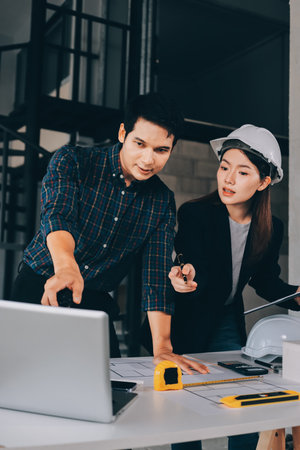 Construction manager and engineer dressed in work vests and hard helmets explore construction documentation on the building site near the steel framesの写真素材