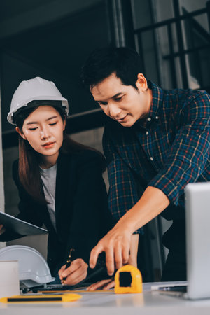 Construction manager and engineer dressed in hard helmets explore construction documentation on the...