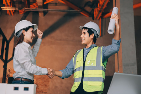 Construction manager and engineer dressed in work vests and hard helmets explore construction documentation on the building site near the steel framesの写真素材
