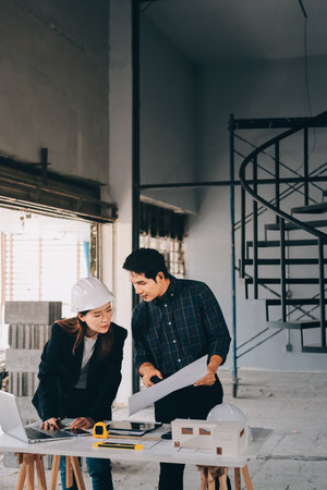 Construction manager and engineer dressed in hard helmets explore construction documentation on the...