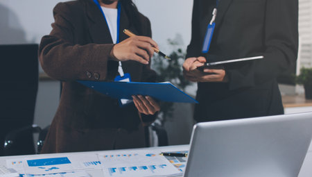 Focused young businessman signing agreement with skilled lawyer in eyeglasses. Concentrated...