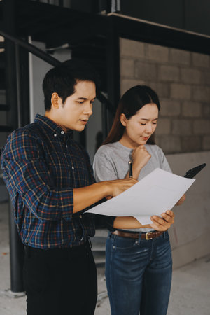 Construction manager and engineer explore construction documentation on the building site near the steel framesの写真素材