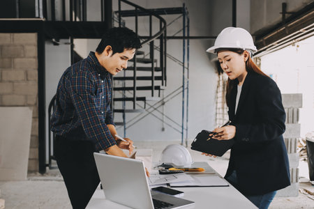 Construction manager and engineer explore construction documentation on the building site near the...