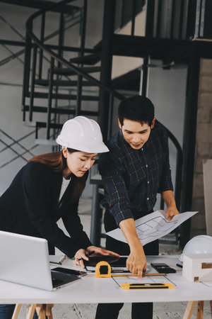 Construction manager and engineer dressed in hard helmets explore construction documentation on the building site near the steel framesの写真素材