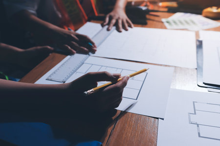 Closeup of team of industrial engineers meeting analyze machinery blueprints consult project on table in manufacturing factory. Working in manufacturing plant or production plant.の写真素材