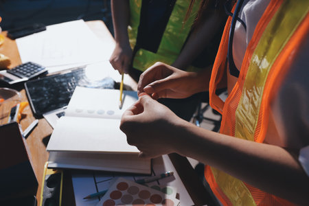 Closeup of team of industrial engineers meeting analyze machinery blueprints consult project on table in manufacturing factory. Working in manufacturing plant or production plant.の写真素材