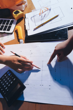 Closeup of team of industrial engineers meeting analyze machinery blueprints consult project on...