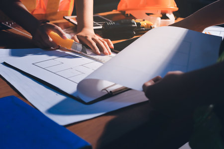 Closeup of team of industrial engineers meeting analyze machinery blueprints consult project on table in manufacturing factory. Working in manufacturing plant or production plant.の写真素材