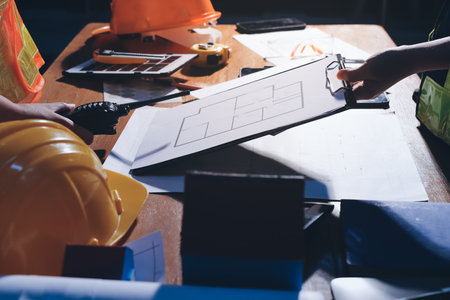 Closeup of team of industrial engineers meeting analyze machinery blueprints consult project on...