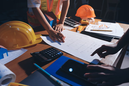 Closeup of team of industrial engineers meeting analyze machinery blueprints consult project on...